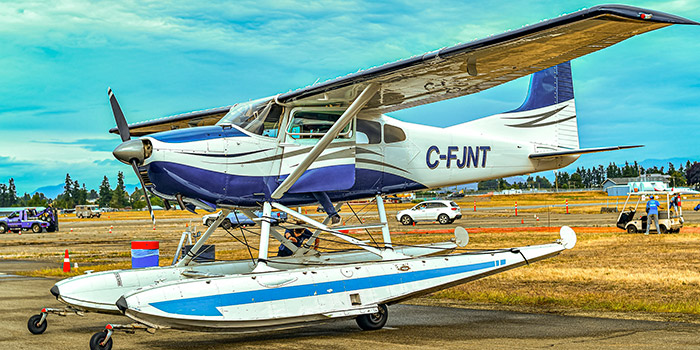 L'image représente un avion amphibie stationné sur un aérodrome sous un ciel bleu éclatant, symbolisant l'innovation en aviation et l'aventure en plein air.