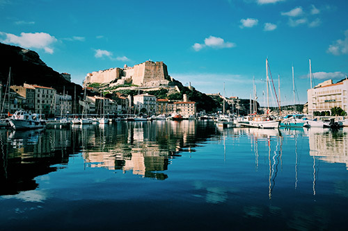 Port pittoresque de Bonifacio avec citadelle surplombant les voiliers, reflet de l'histoire et de la culture corse.