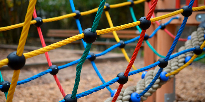 Dans un parc animé, un réseau coloré de cordes constitue un équipement de jeu attrayant pour les enfants, promouvant l'activité physique et la coopération.