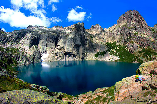 Image d'un lac de montagne aux eaux cristallines reflétant le ciel bleu éclatant, entouré de sommets rocheux majestueux. Un paysage qui évoque la tranquillité et la grandeur naturelle.