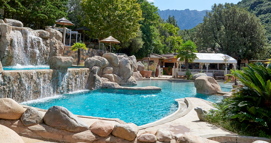 Une piscine naturelle idyllique entourée de rochers, illuminée par le soleil et agrémentée de végétation luxuriante, pour une détente parfaite en pleine nature.