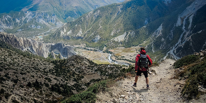 Randonneur au sommet admirant un paysage montagneux inspirant, symbole d'évasion et d'aventure en pleine nature.