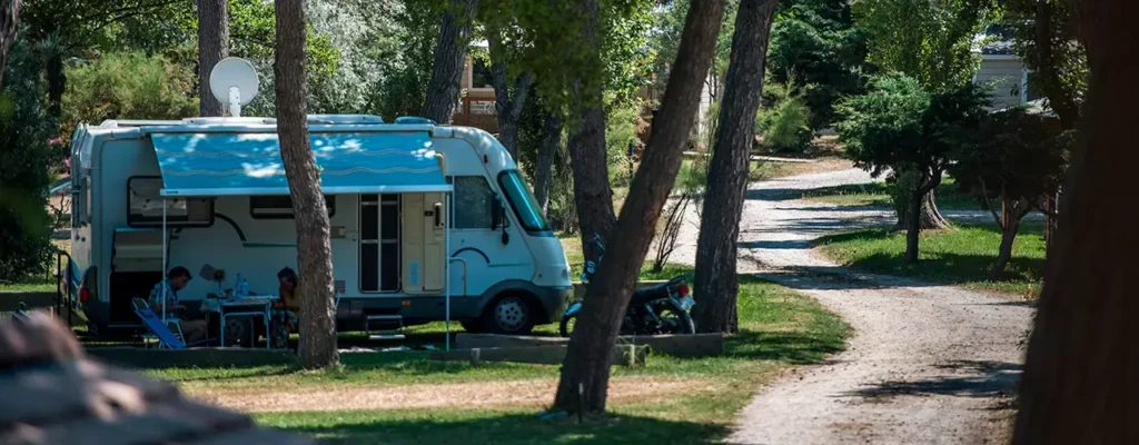 camping-corse-bord-de-mer-luxe-09 Camping-car stationné sur un emplacement ombragé et arboré d'un camping pour un séjour de vacances et partir en camping car en Corse du Sud.