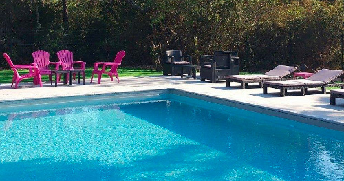 Scène de relaxation estivale avec chaises longues colorées au bord d'une piscine scintillante entourée de verdure, parfait pour une journée ensoleillée.