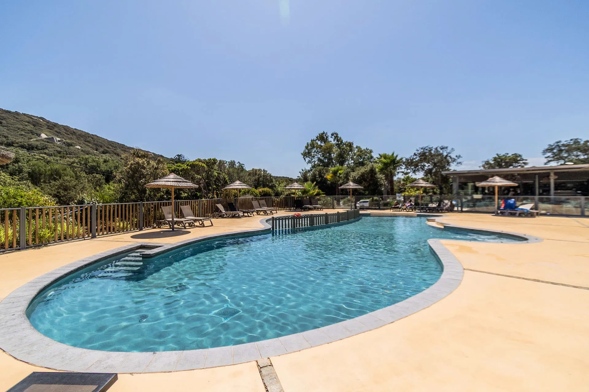 Piscine lagon sécurisée avec pataugeoire au Camping Le Damier, vue sur le maquis corse.