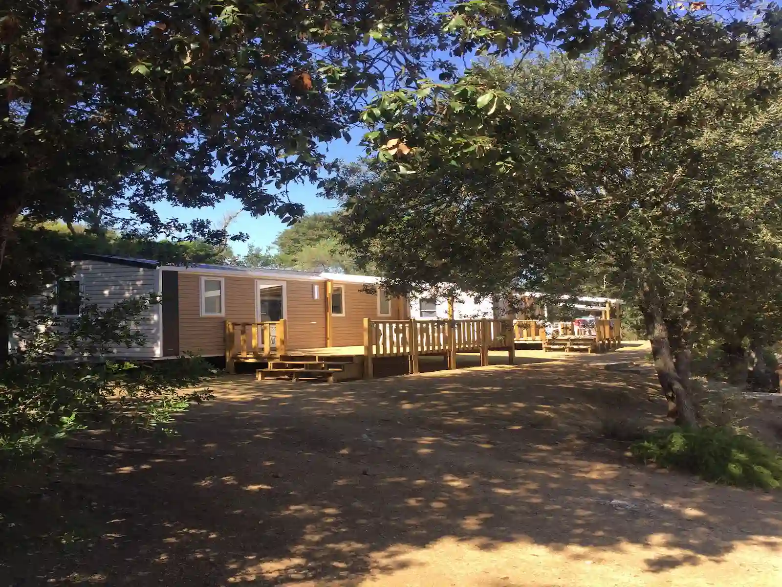 Mobil-homes avec terrasse vue sur les collines corses sous un ciel bleu.