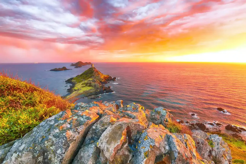 Les Îles Sanguinaires au coucher du soleil Silhouette des Îles Sanguinaires et de la tour génoise d'Ajaccio sous un ciel flamboyant au crépuscule.