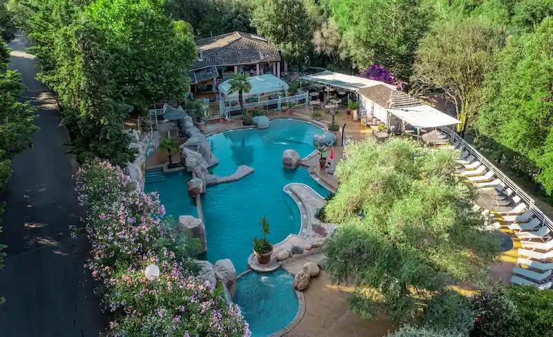 Bassin de baignade turquoise avec cascades et rochers naturels au Camping Les Oliviers.