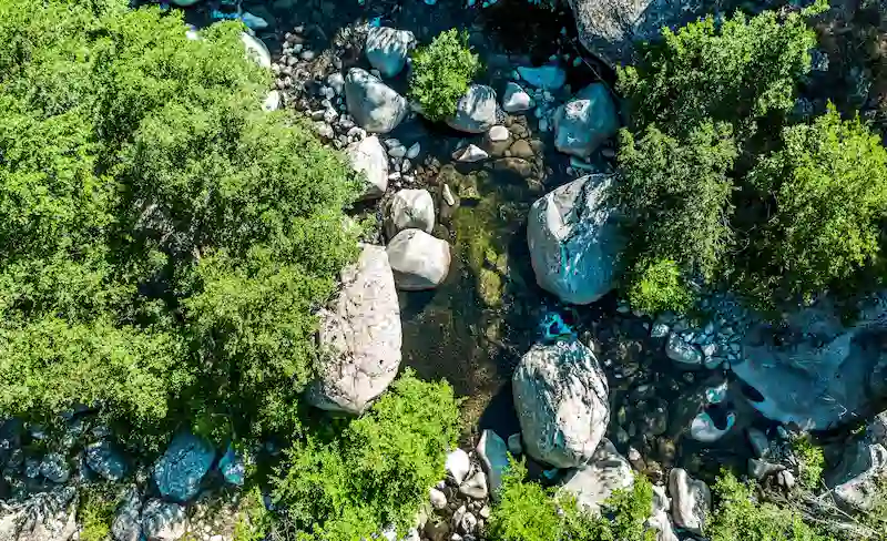 Vue d'ensemble des bâtiments et des piscines du camping intégrés dans la pente de la montagne.