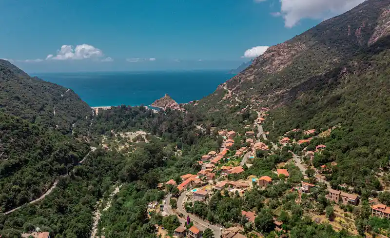 Panorama sur le village de Porto, la tour génoise et la mer Méditerranée entre deux montagnes.