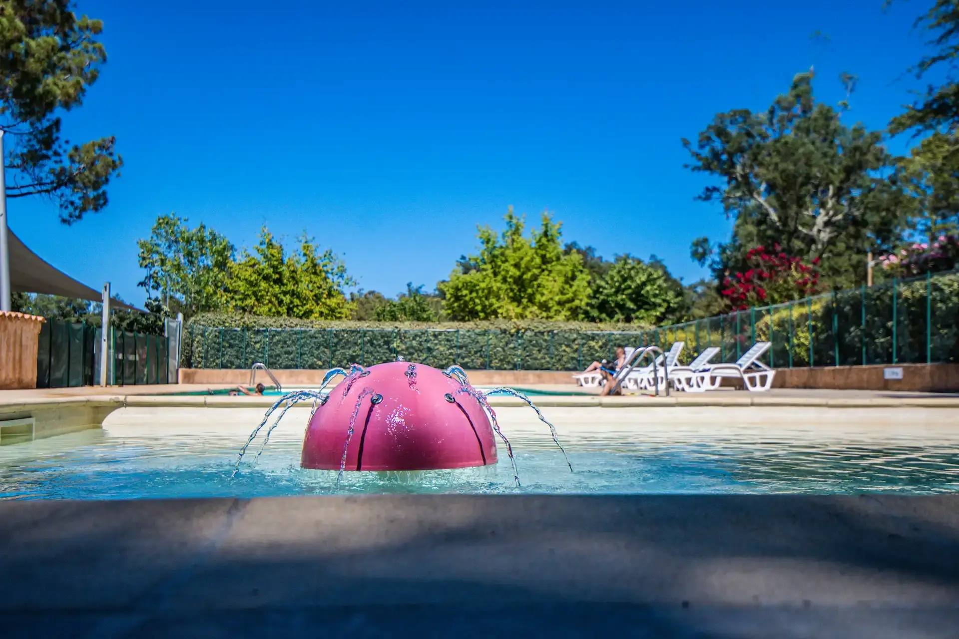 Perspective de la piscine turquoise du camping Santa Lucia sous un ciel bleu sans nuage.
