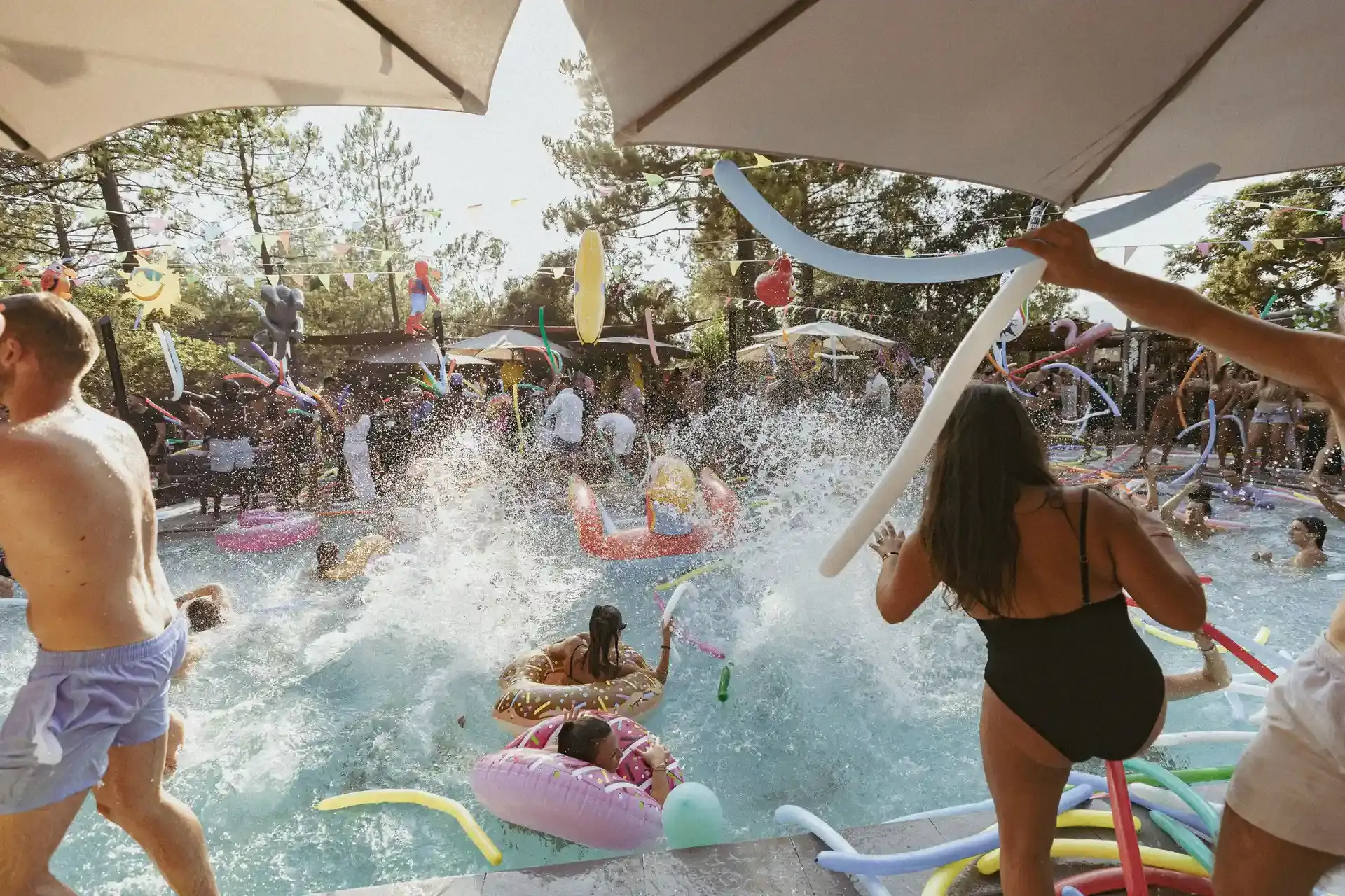Des dizaines de campeurs s'amusent et dansent dans la piscine du Camping U Stabiacciu à Porto-Vecchio, avec des frites de piscine et des bouées colorées, lors d'une journée ensoleillée.