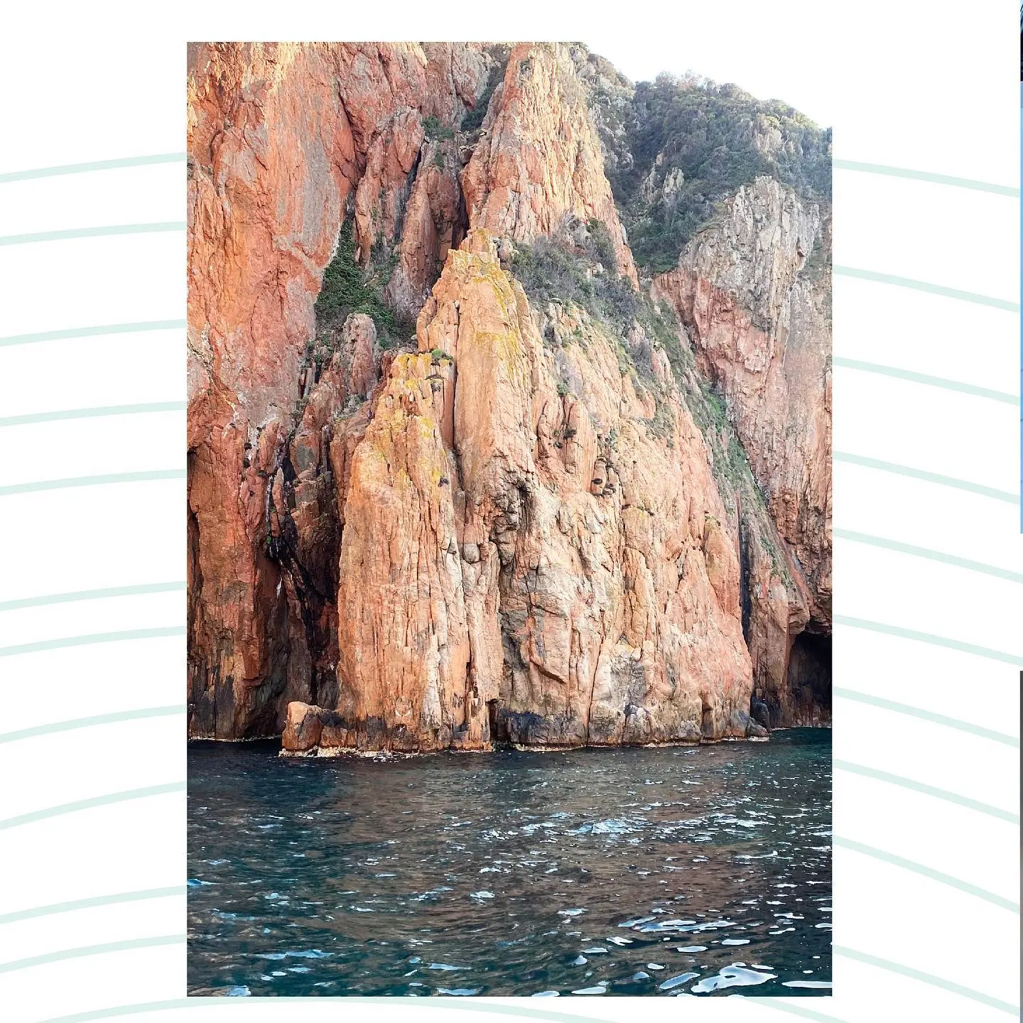 Imposantes falaises rocheuses de couleur ocre, rouge et orange, parsemées de maquis vert, s'élevant verticalement au-dessus d'une mer bleu foncé, vues depuis l'eau lors d'une balade en bateau près des Calanques de Piana en Corse.