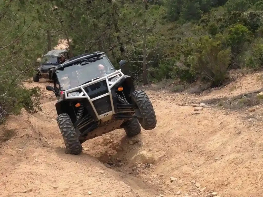 terrain-sinueux-adrénaline-buggy-activité-insolite-corse-corsica-ranger Buggy Polaris RZR en pleine action sur un terrain sablonneux sinueux avec une roue avant levée lors d'un virage technique.