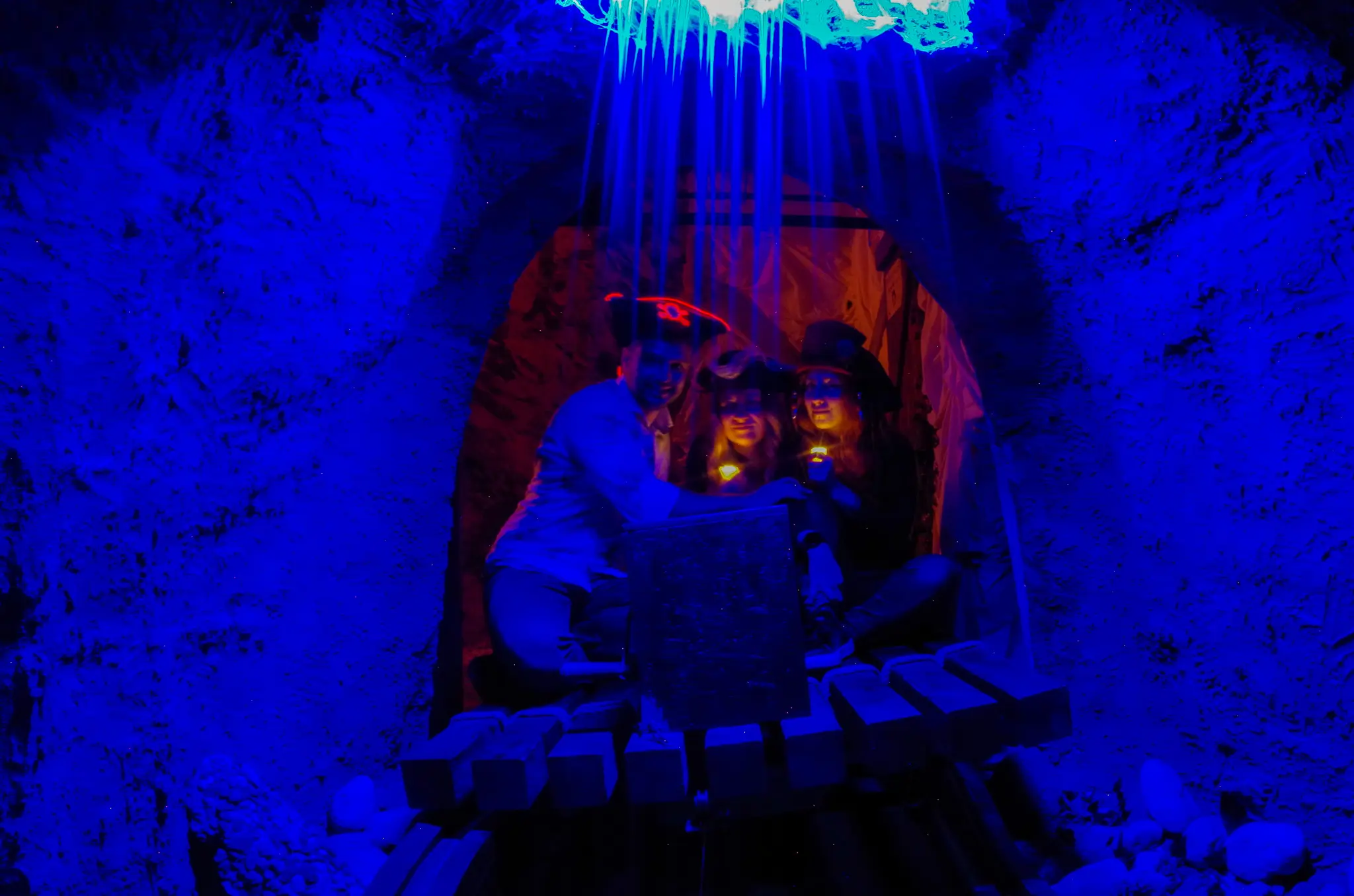 Groupe de joueurs célébrant la découverte d'un coffre sous une lumière bleue mystique dans une grotte de pirate.