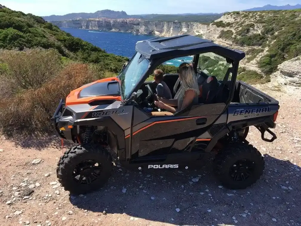 Buggy Polaris General stationné sur une crête offrant une vue panoramique sur les falaises de calcaire et la mer près de Bonifacio.